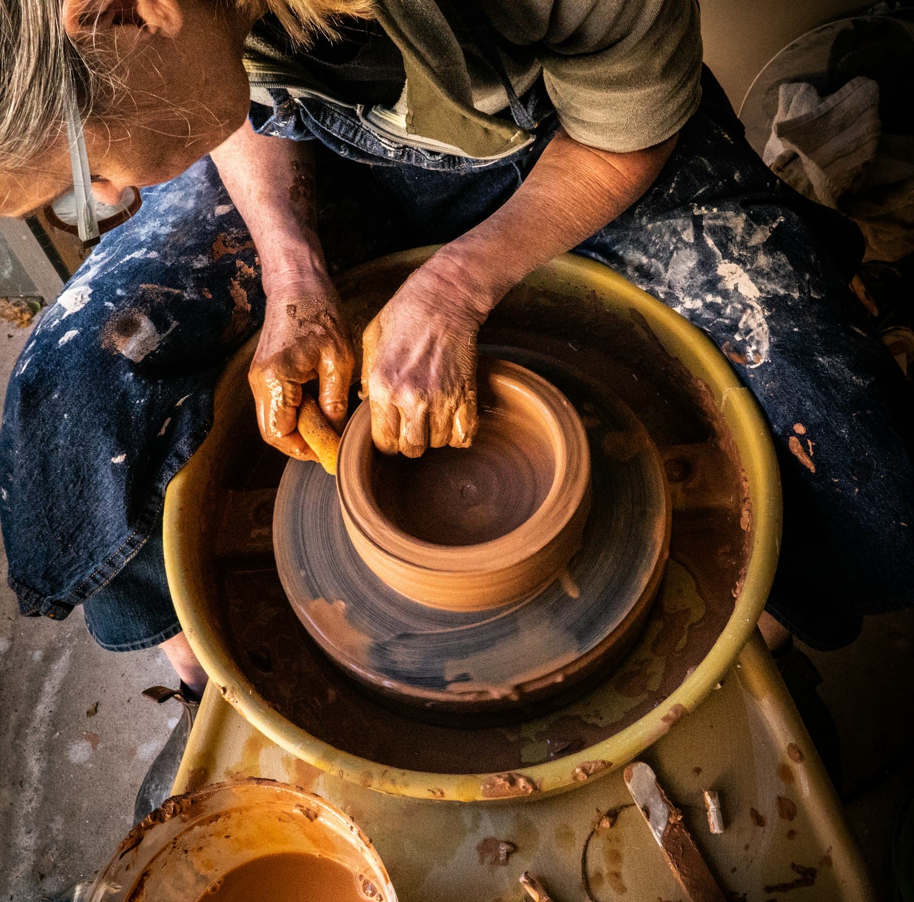 Hands shaping a terracotta pot on the wheel